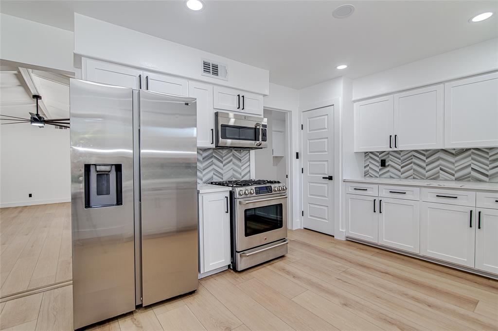 7992 Fallmeadow Lane Dallas, TX 75248 - Photo 14 of 30 a kitchen with stainless steel appliances white cabinets a sink a stove a refrigerator and white cabinets