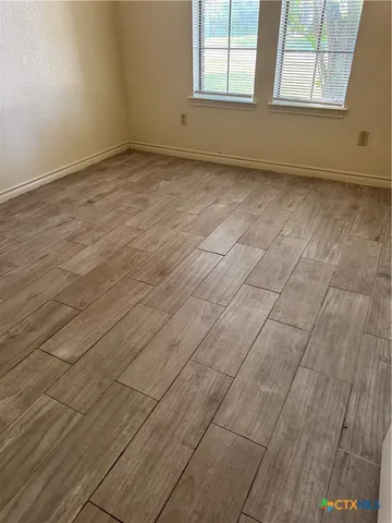 an empty room with wooden floor and windows