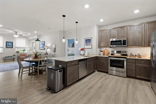 a kitchen with stainless steel appliances kitchen island granite countertop a stove top oven a sink a dining table and chairs