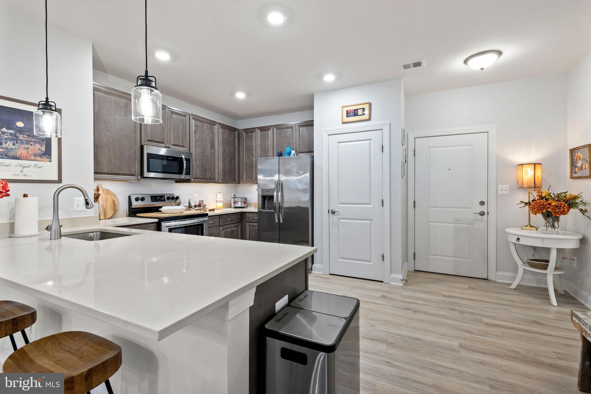 403 Bold Ruler Court, Unit 405 Havre de Grace, MD 21078 - Photo 5 of 32 a kitchen with stainless steel appliances a refrigerator a stove a sink a dining table and chairs with wooden floor