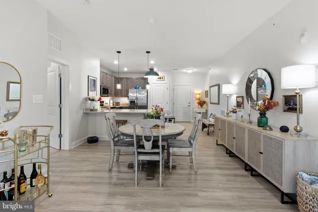 a kitchen with stainless steel appliances kitchen island granite countertop a table chairs in it and wooden floors