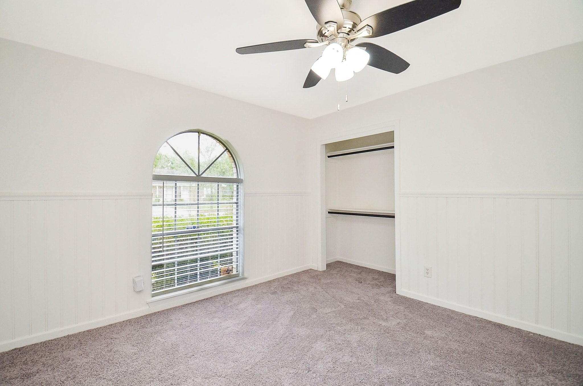 9014 Langfield Road Houston, TX 77040 - Photo 17 of 37 This bright and inviting bedroom offers soft neutral tones, plush gray carpeting, and classic wainscoting paneling that adds elegant architectural detail.