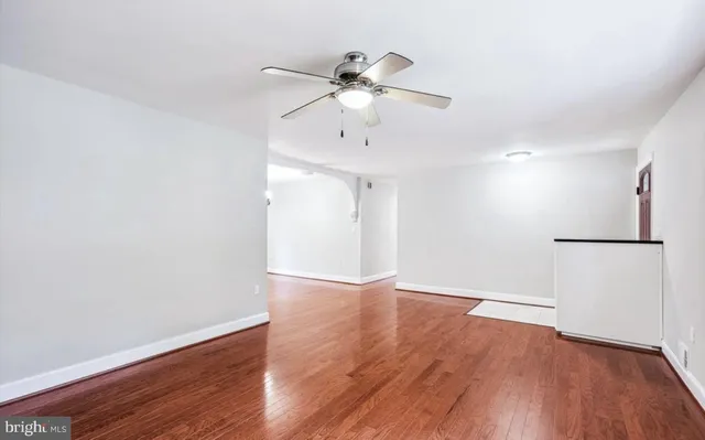 an empty room with wooden floor ceiling fan and window