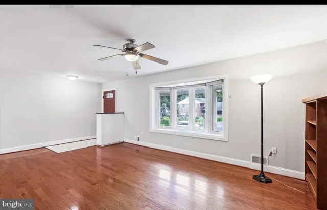 a view of empty room with wooden floor and fan