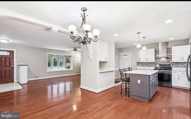 a open kitchen with stainless steel appliances granite countertop a refrigerator a stove top oven a sink dishwasher and white cabinets with wooden floor