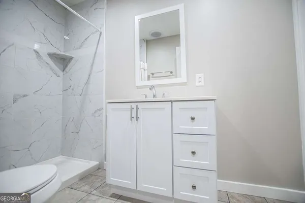 a bathroom with a granite countertop sink toilet and shower