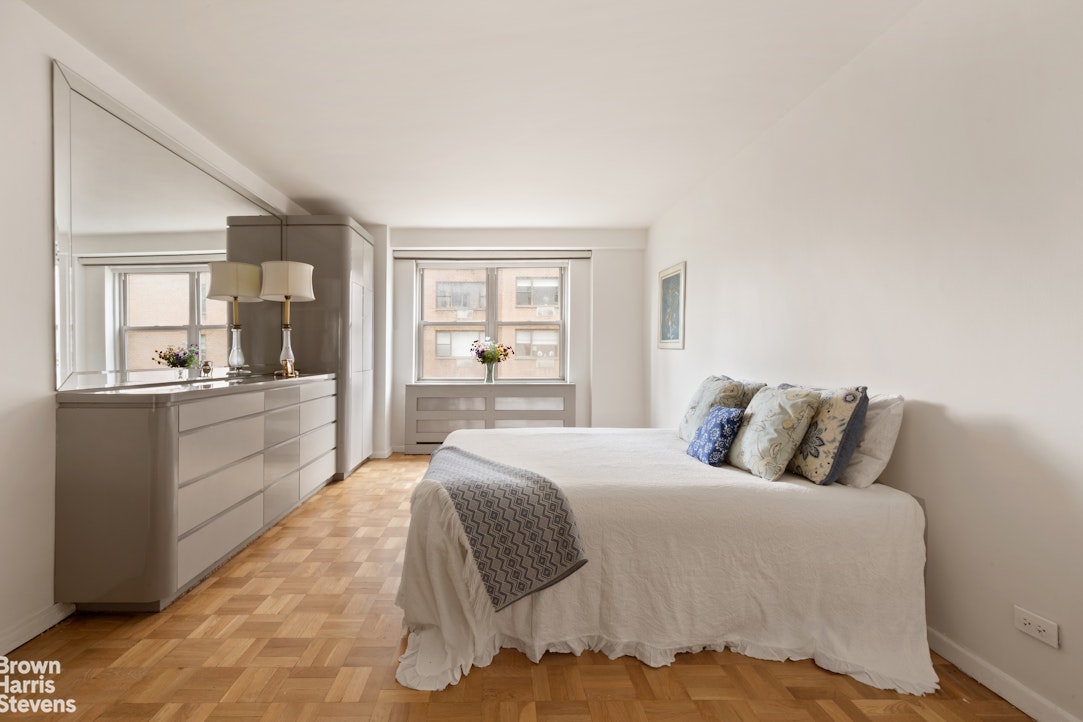 135 East 83rd Street, Unit 7A Manhattan, NY 10028 - Photo 4 of 8 a bedroom with a large bed and a view of kitchen