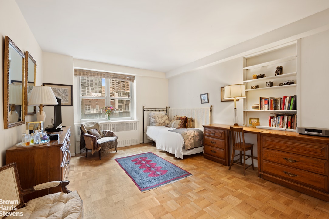 135 East 83rd Street, Unit 7A Manhattan, NY 10028 - Photo 6 of 8 a bedroom with furniture and a book shelf