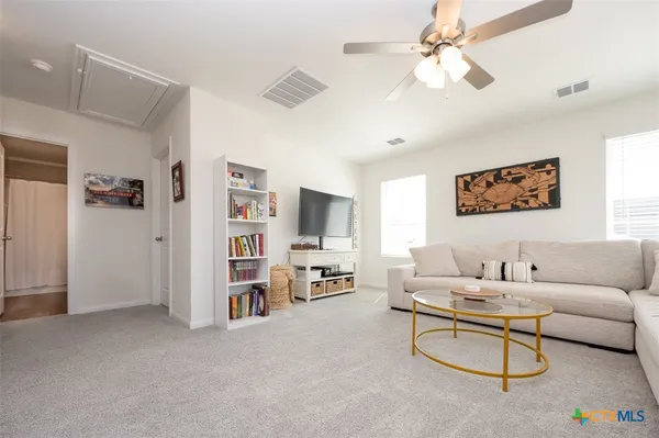 a living room with furniture a ceiling fan and a bookshelf