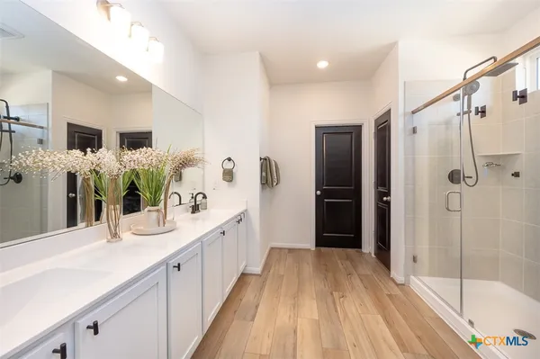 a spacious bathroom with a double vanity sink a large mirror a bathtub and shower
