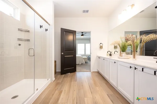 a large white bathroom with a double vanity sink a large mirror a shower and bathtub