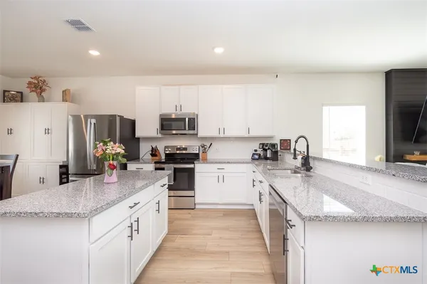 a kitchen with granite countertop a sink a counter top space appliances and cabinets