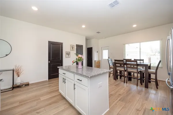 a view of kitchen island dining room wooden floor and stainless steel appliances