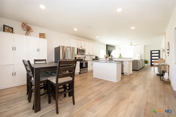 a kitchen with stainless steel appliances kitchen island granite countertop a table chairs and a refrigerator