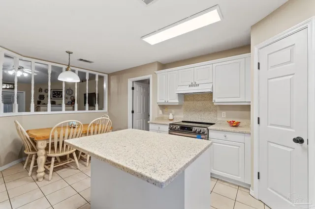 a kitchen with stainless steel appliances kitchen island granite countertop a table chairs and a refrigerator