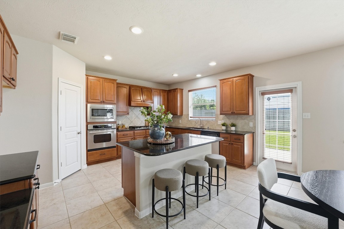 17415 Memorial Mills Drive Spring, TX 77379 - Photo 13 of 37 a kitchen with stainless steel appliances kitchen island granite countertop a refrigerator and a stove top oven