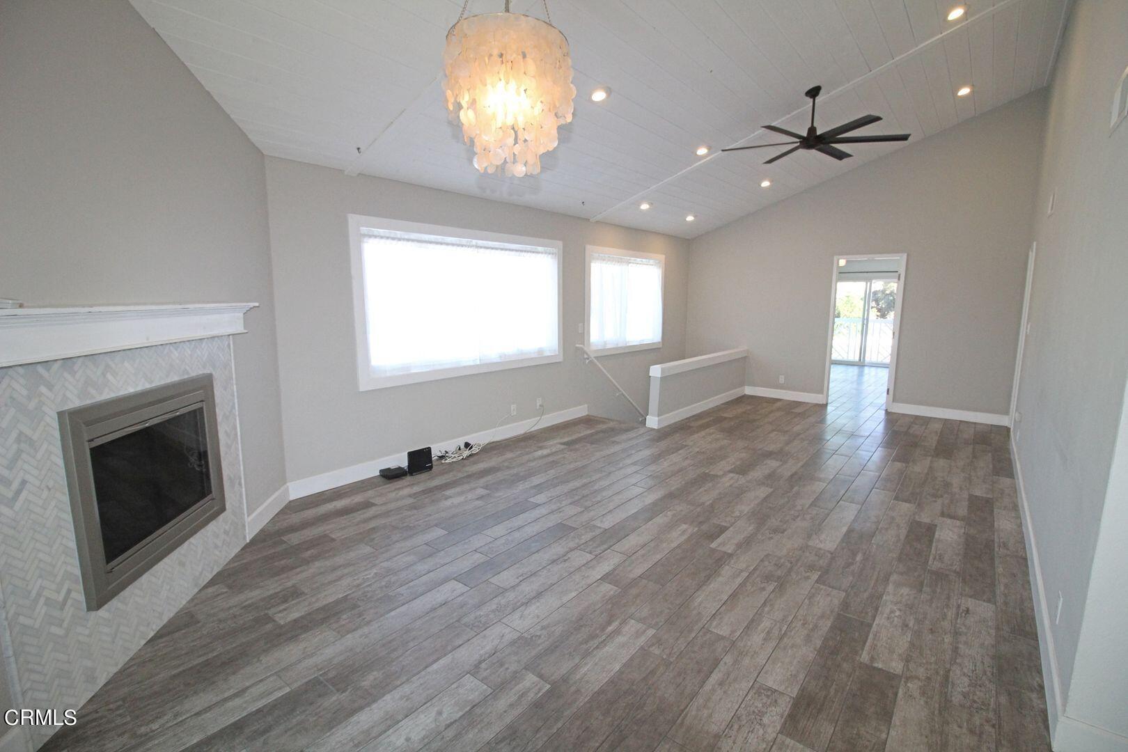 4185 Sunset Lane Oxnard, CA 93035 - Photo 9 of 32 an empty room with wooden floor fireplace and windows