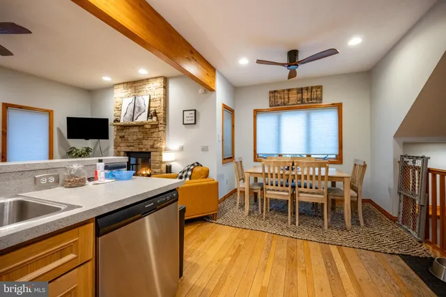 a kitchen with stainless steel appliances granite countertop a sink a stove a dining table and chairs with wooden floor