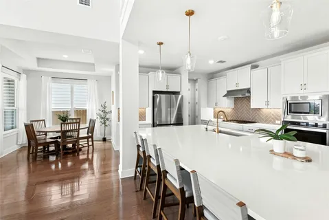 a kitchen with stainless steel appliances granite countertop a stove a refrigerator a kitchen island a dining table and chairs