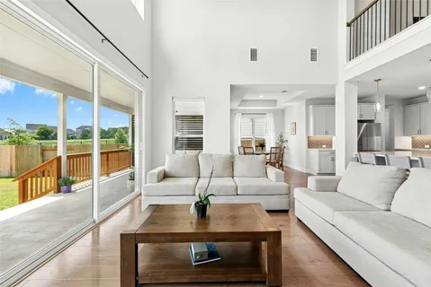 a living room with furniture large windows and wooden floor