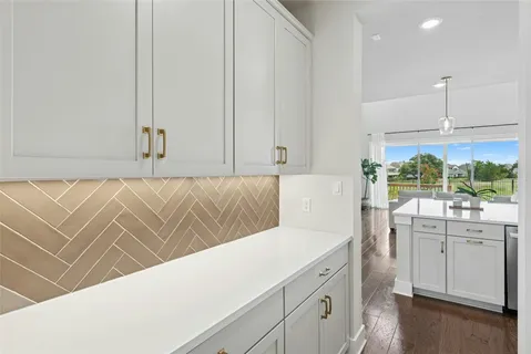 a view of a kitchen with white cabinets and wooden floor