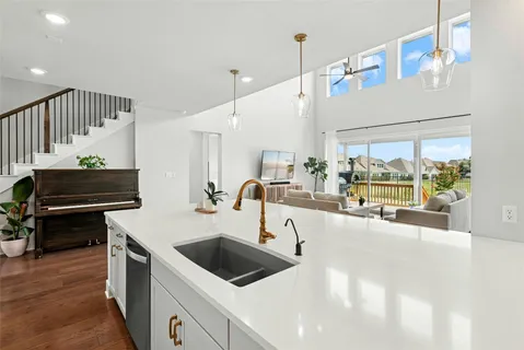 a kitchen with kitchen island a large counter top a stove a chimney a sink and a large window