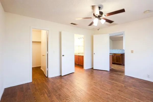 an empty room with wooden floor and ceiling fan