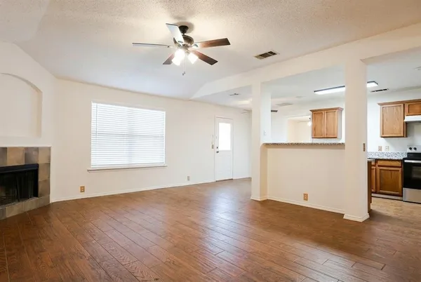 a view of an empty room with a kitchen and a window