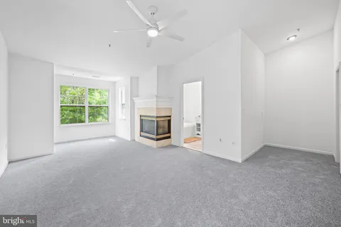 an empty room with windows fireplace and a ceiling fan