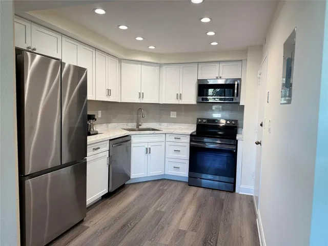 a kitchen with a refrigerator a stove top oven a sink and cabinets