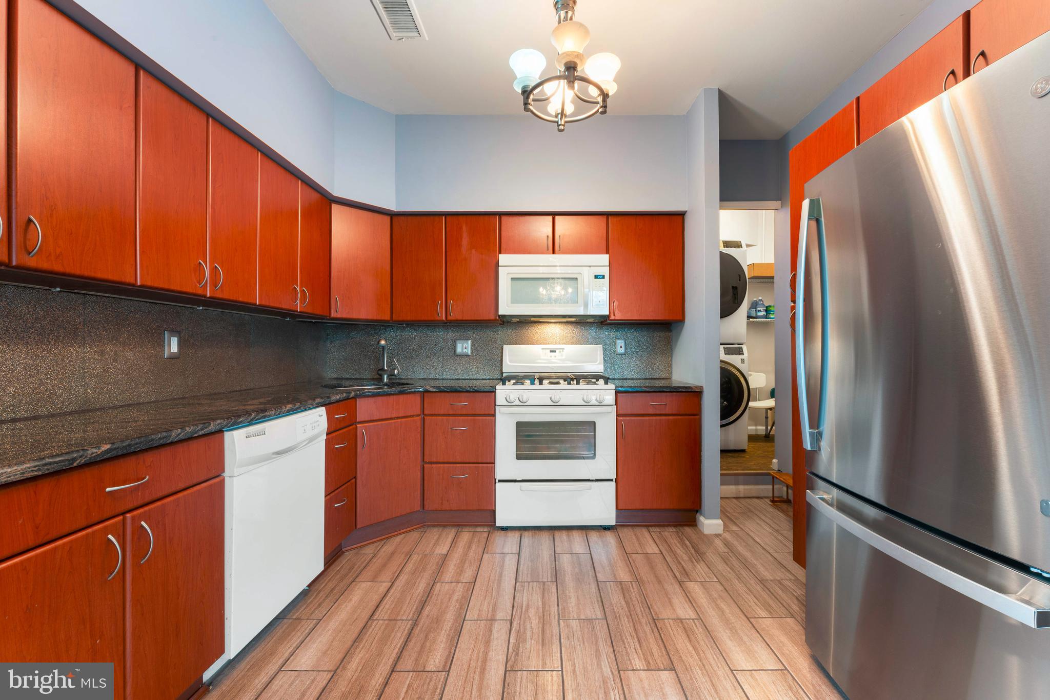 301 Byberry Road, Unit F1 Philadelphia, PA 19116 - Photo 12 of 30 a kitchen with stainless steel appliances granite countertop a refrigerator a sink dishwasher a stove and white countertops with wooden floor