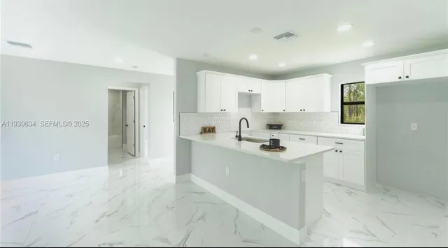 a kitchen with a sink a stove a refrigerator and white cabinets
