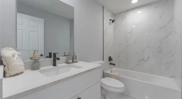 a bathroom with a granite countertop sink a toilet and a bathtub