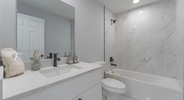 a bathroom with a granite countertop sink a toilet and a bathtub