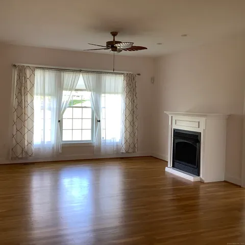an empty room with wooden floor fireplace and windows