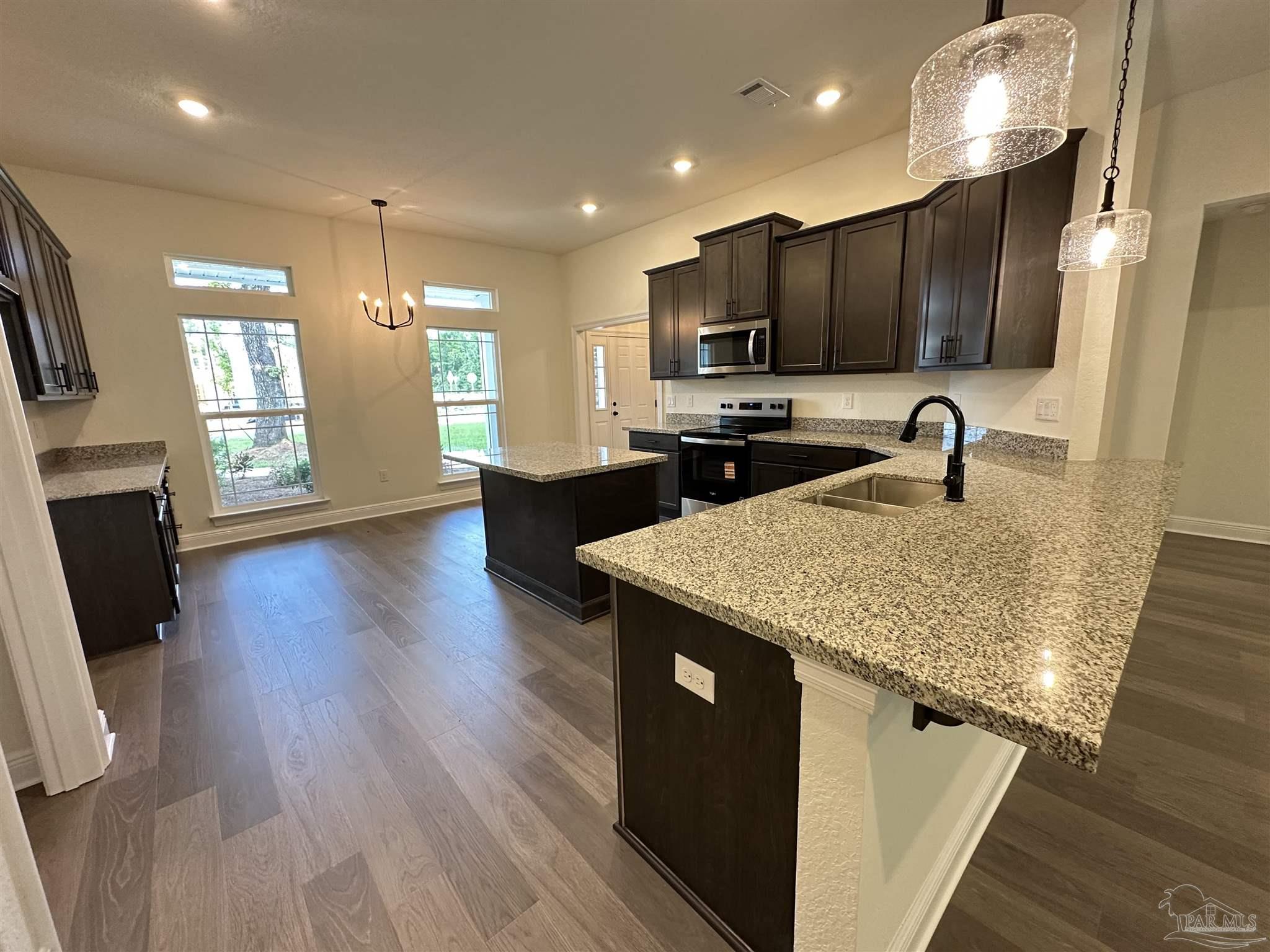 5214 Barnett Road Milton, FL 32583 - Photo 6 of 22 a kitchen with stainless steel appliances granite countertop a sink a stove and a wooden floors