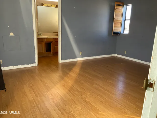 an empty room with wooden floor cabinet and windows