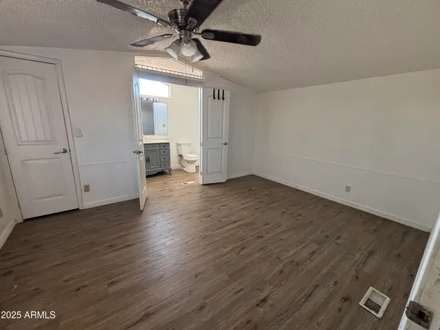 an empty room with wooden floor staircase and windows