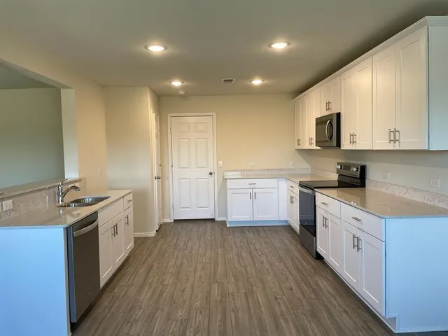 a large kitchen with a lot of counter space and wooden floor