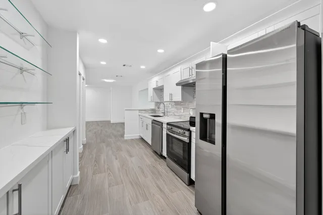 a large kitchen with a center island wooden floor stainless steel appliances and cabinets