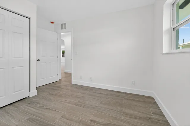 a view of an empty room with wooden floor and a window