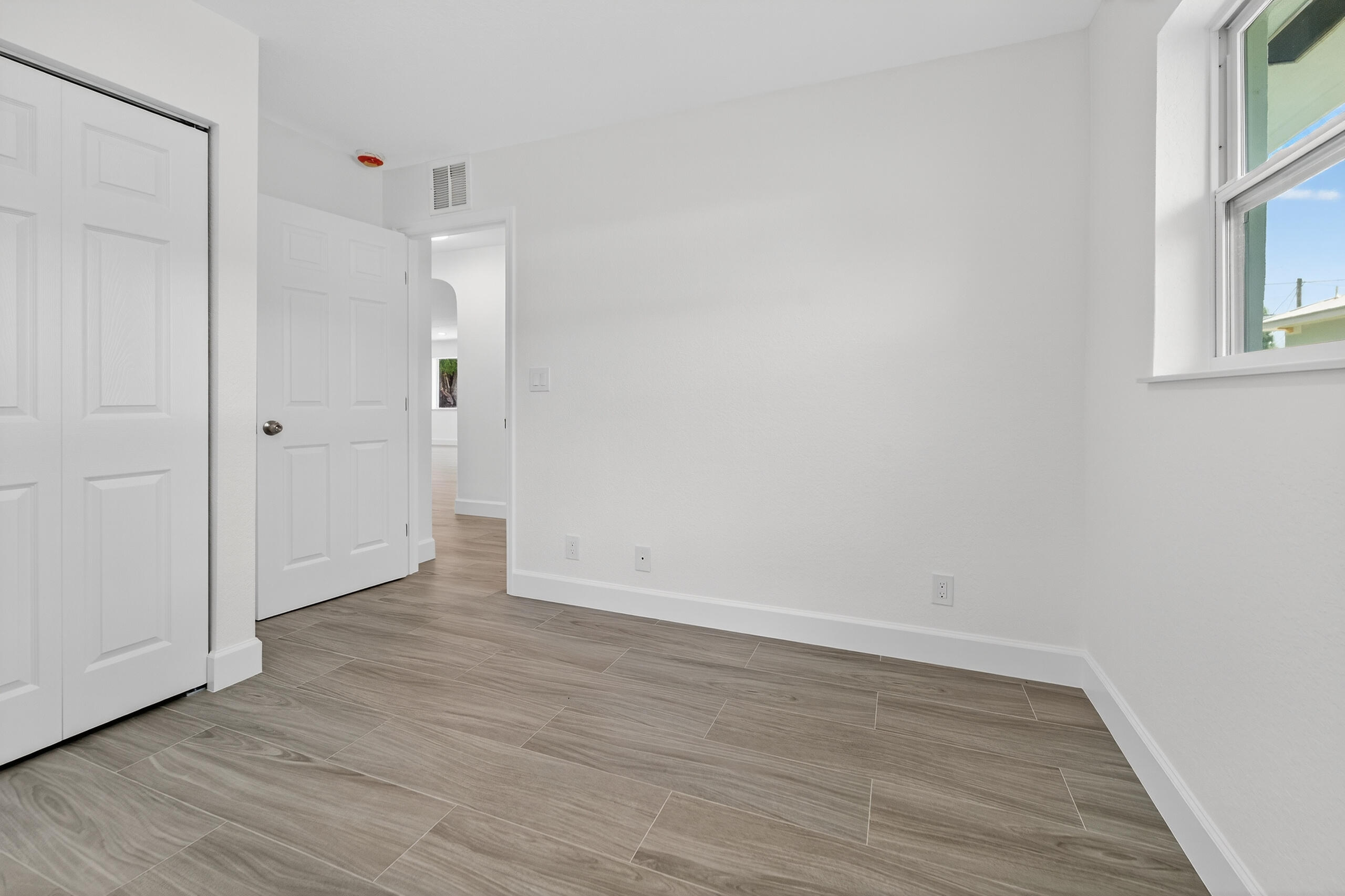 6830 2nd Street Jupiter, FL 33458 - Photo 14 of 34 a view of an empty room with wooden floor and a window