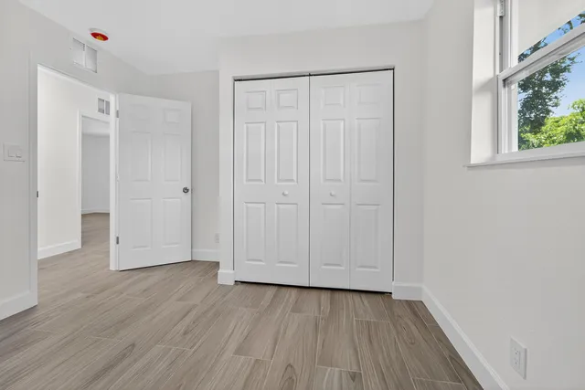 a view of an empty room with wooden floor and a window