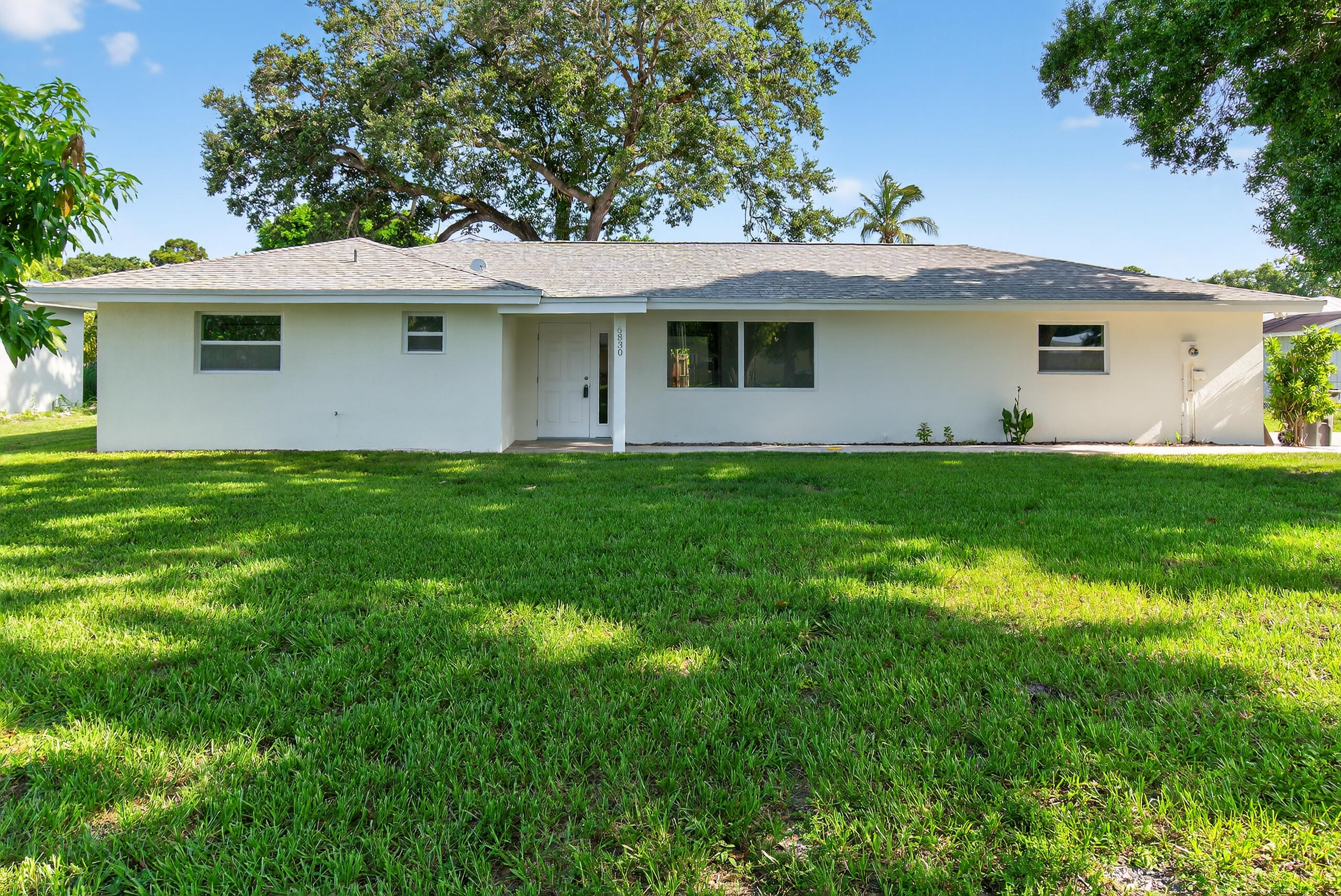 6830 2nd Street Jupiter, FL 33458 - Photo 2 of 34 a front view of a house with a garden