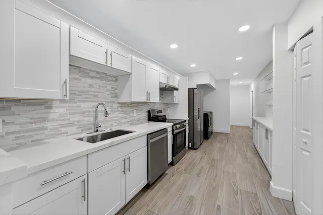 a kitchen with a sink a counter top space stainless steel appliances and cabinets