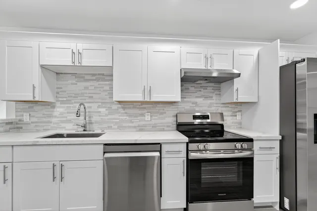 a kitchen with stainless steel appliances granite countertop white cabinets and a stove a oven with white countertops