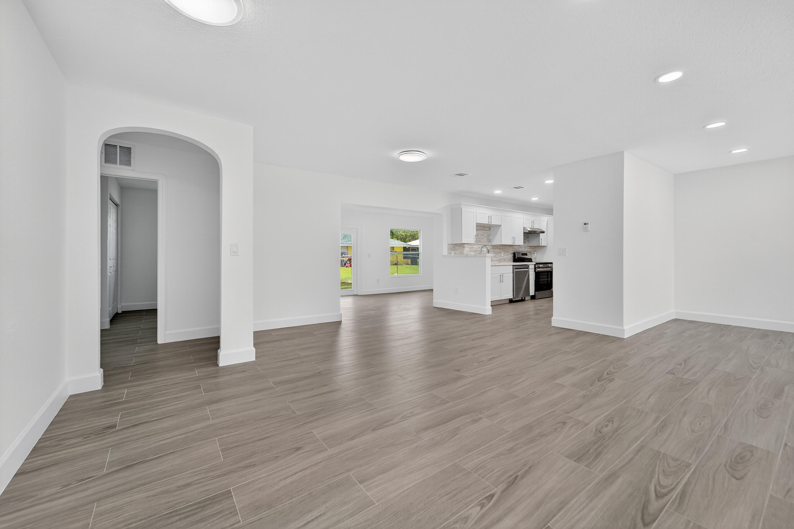 6830 2nd Street Jupiter, FL 33458 - Photo 5 of 34 a view of an empty room with wooden floor and a kitchen