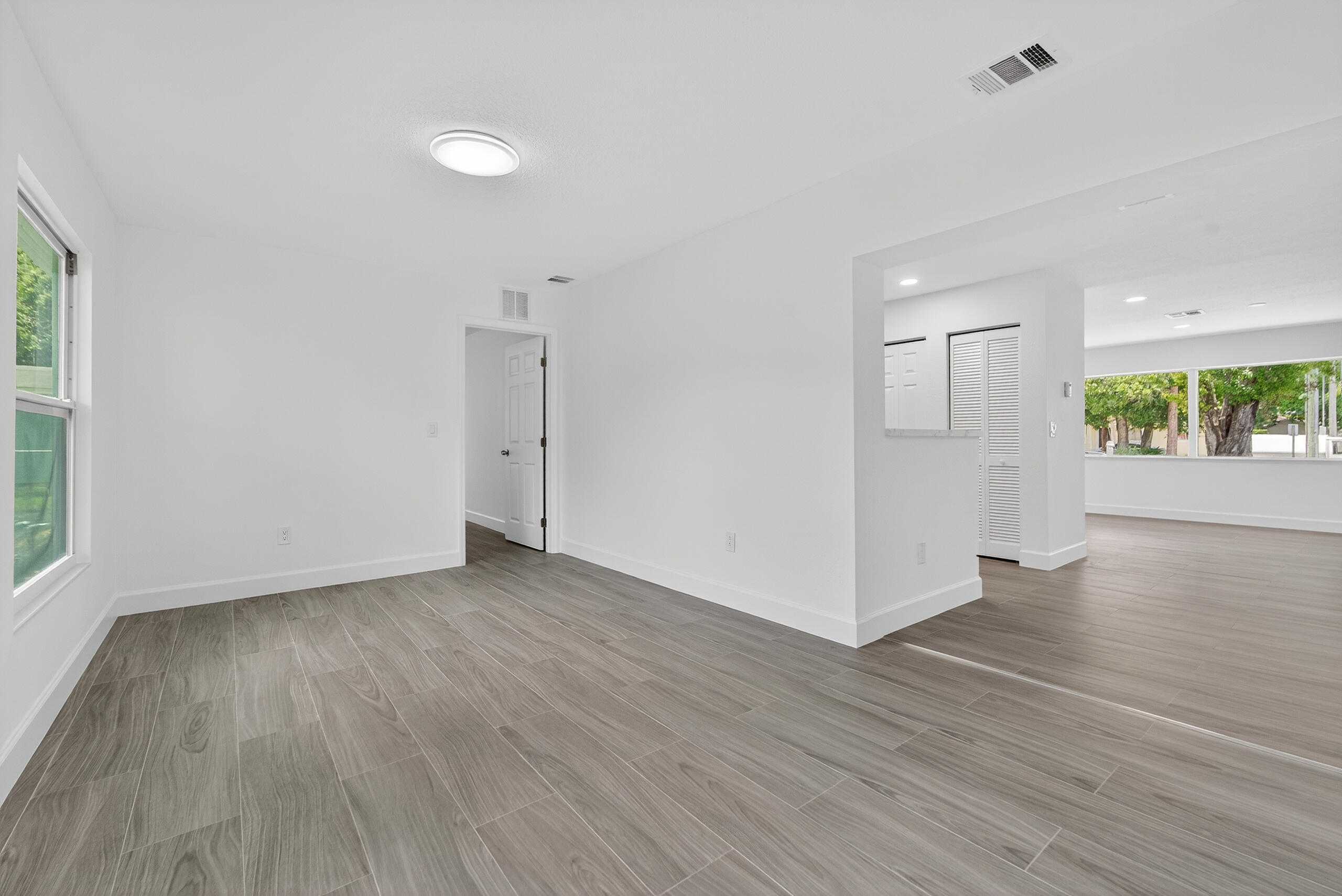 6830 2nd Street Jupiter, FL 33458 - Photo 7 of 34 a view of an empty room with wooden floor and a window