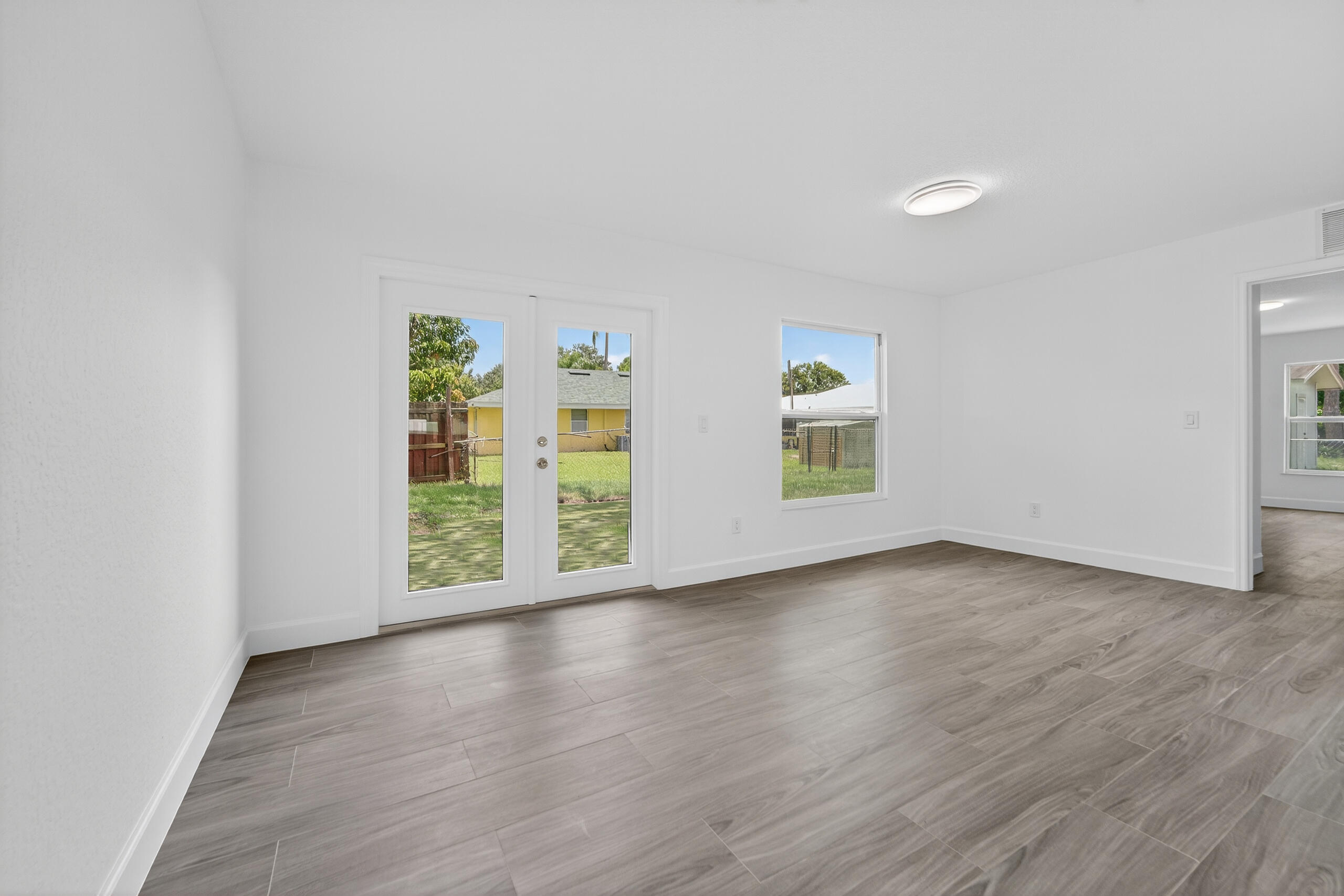 6830 2nd Street Jupiter, FL 33458 - Photo 8 of 34 an empty room with wooden floor and windows