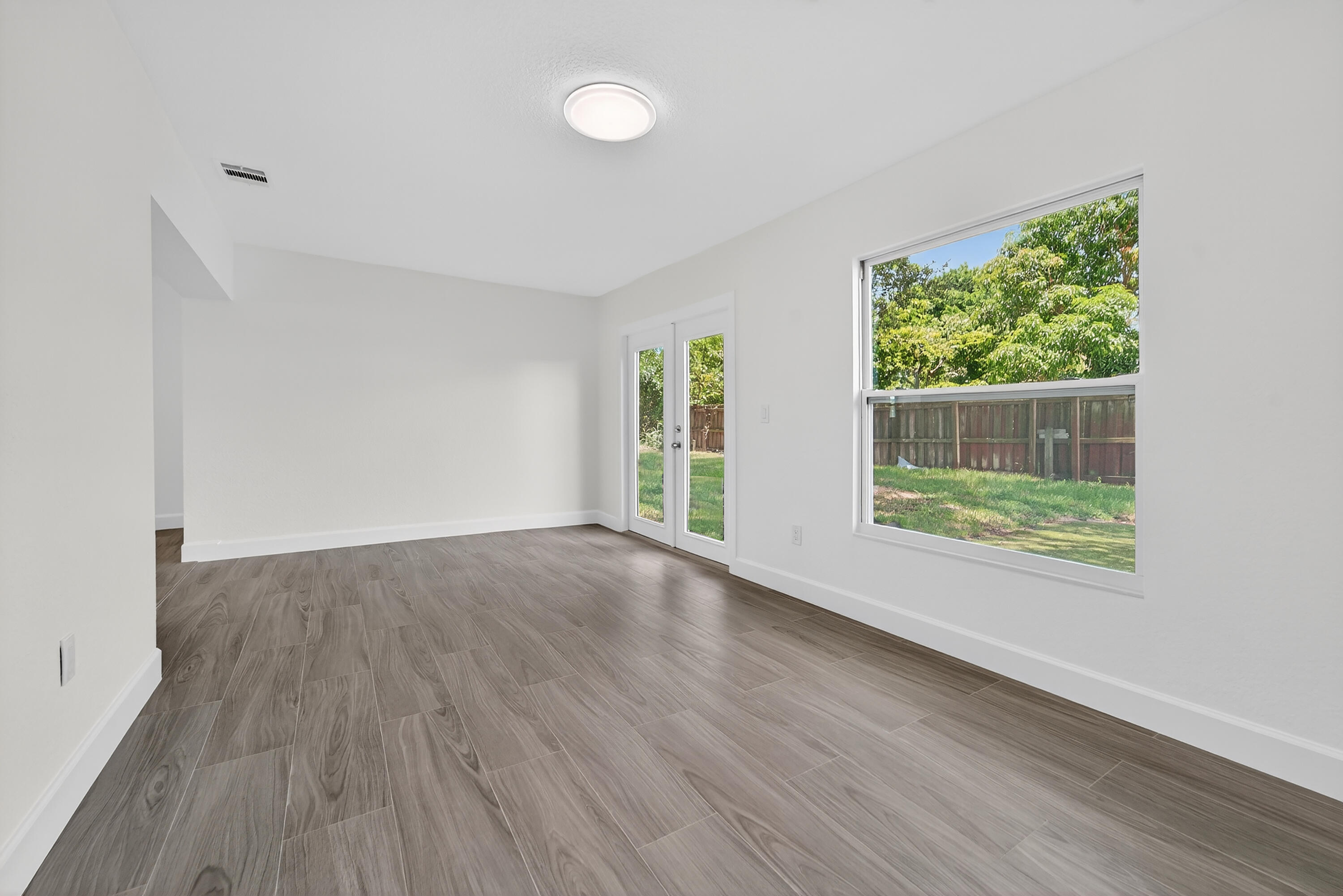 6830 2nd Street Jupiter, FL 33458 - Photo 9 of 34 a view of an empty room with wooden floor and a window